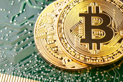 Golden Bitcoin Cryptocurrency on computer circuit board. Macro shot